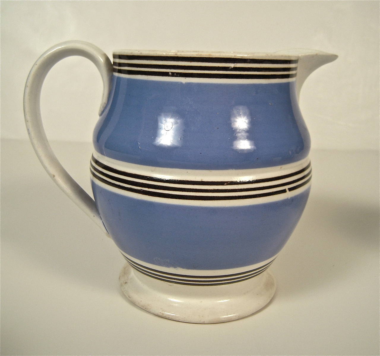 A collection of five 19th century blue, black and white stripe-decorated Staffordshire mochaware pottery, comprising a slip-banded jug, quart mug and three pint mugs, English, circa 1840-1880. Acquired and sold as a
