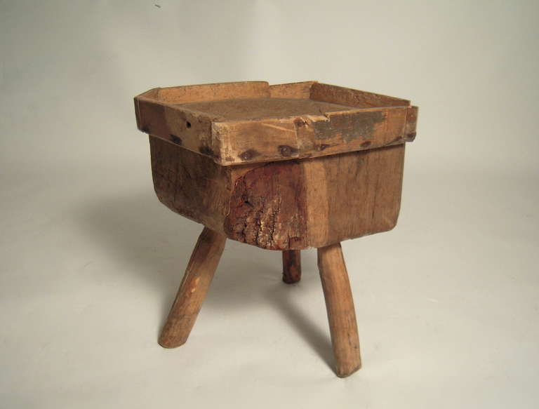 A primitive  butcher block side table, the top concave form wear, surrounded by a simple 'gallery', raised on 3 legs. Charming, sturdy side table.