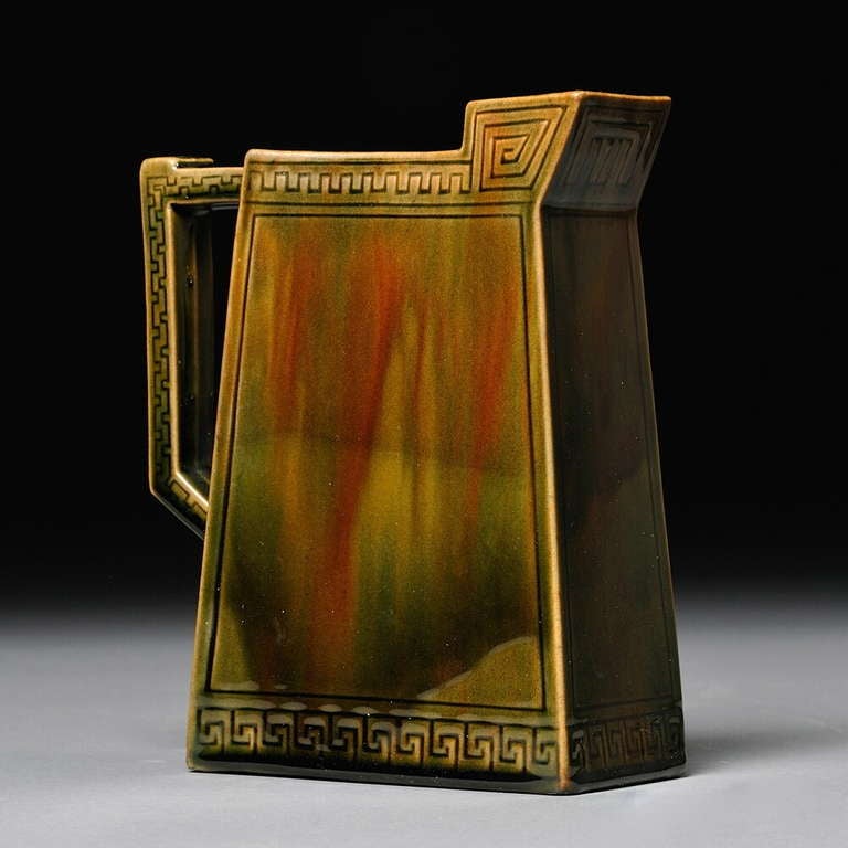 A graphic and sculptural Chelsea Keramic Art Works Pitcher Chelsea, Massachusetts, c. 1882-1889, of trapezoidal form, with spout and handle, in olive green glaze decorated with impressed Greek key borders, the base impressed Chelsea Keramic Art