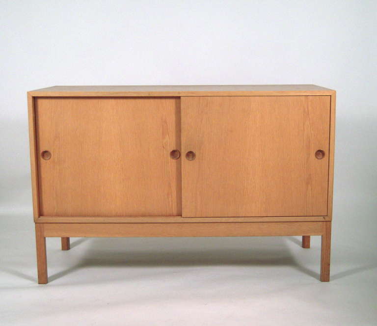 A Borge Møgensen Øresund credenza cabinet, or sideboard, in light oak, of rectangular form, the two sliding doors with inset circular pulls in contrasting darker wood, enclosing an interior fitted with 2 white lacquered sliding drawers over 2 long