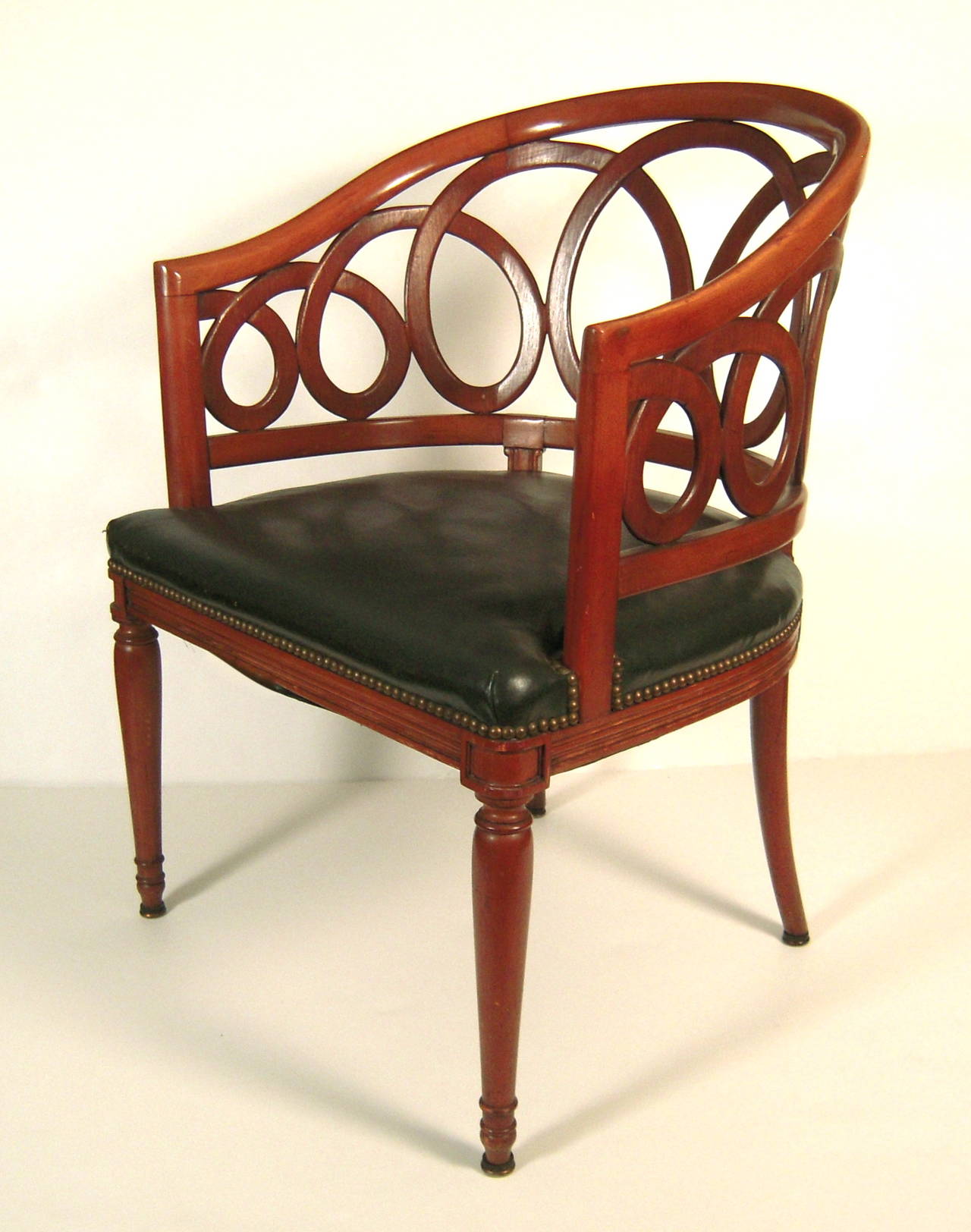 A stylish and graphic barrel back chair in fruitwood, in the style of Frances Elkins, the curved back with interlaced, looping design, over a conforming leather upholstered seat, raised on inverted tapering cylindrical legs.