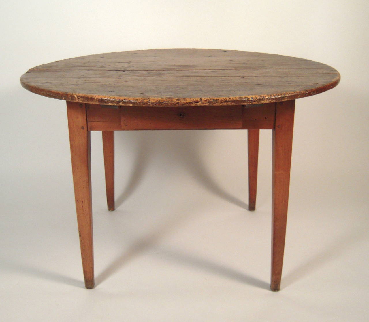 An inventive and unusual, American country two-part dining table in chestnut, the circular, free-standing portion from the late 18th or early 19th century, with a later, racetrack shaped extension, with hinged folding legs, which easily slides in to