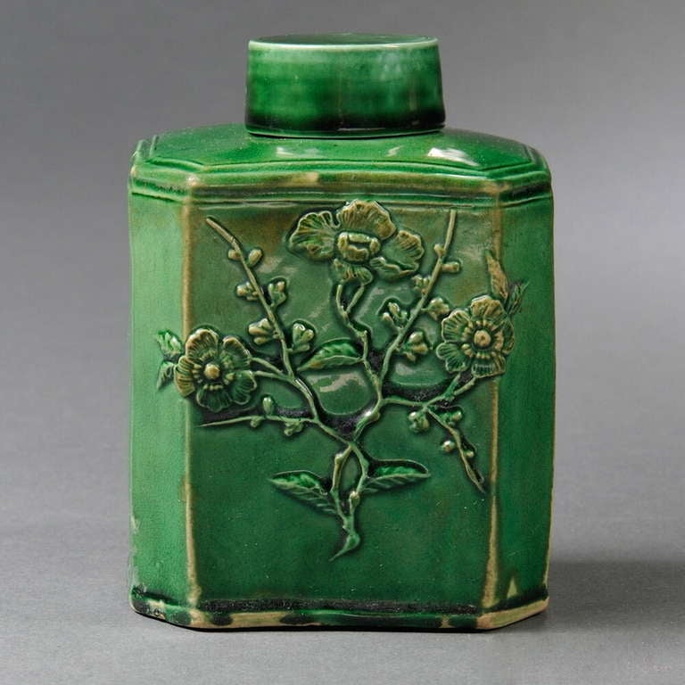 An 18th century English Staffordshire green glazed ceramic tea canister, circa 1765, inspired by Chinese metal and ceramic forms, of rectangular form with canted corners, with applied press-molded prunus blossom decoration to both sides, with cover.