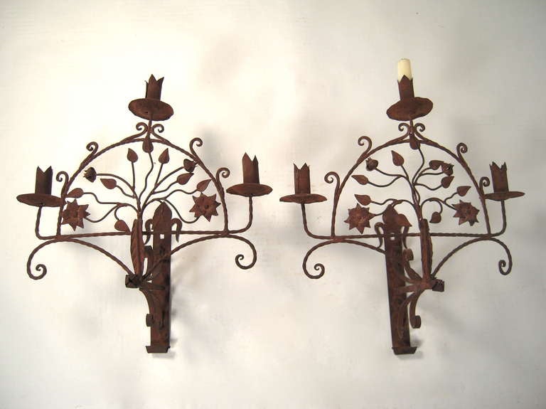 A pair of large, decorative Spanish wrought iron 3-light sconces.