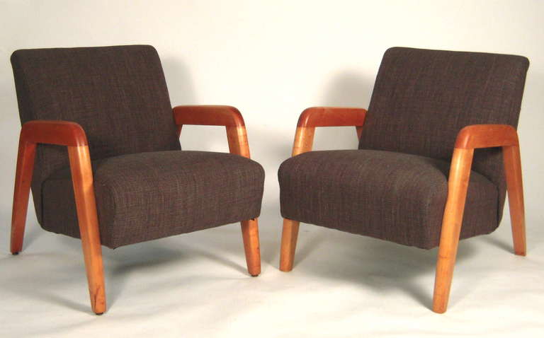 A pair of stylish midecentury modern upholstered armchairs, with continuous angled maple arms and legs, newly  upholstered in charcoal grey linen blend.
Newly restored and reupholstered.