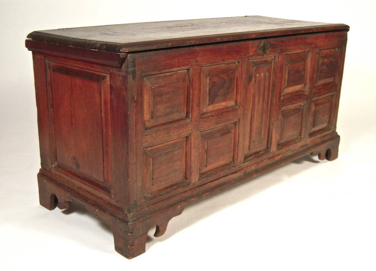 An American Southern, likely Eastern Shore, Maryland or Virginia, made blanket chest in walnut stained yellow pine, of rectangular, architectural form, the lift top lid over carved fielded panels on the sides and front, centered by a vertical panel