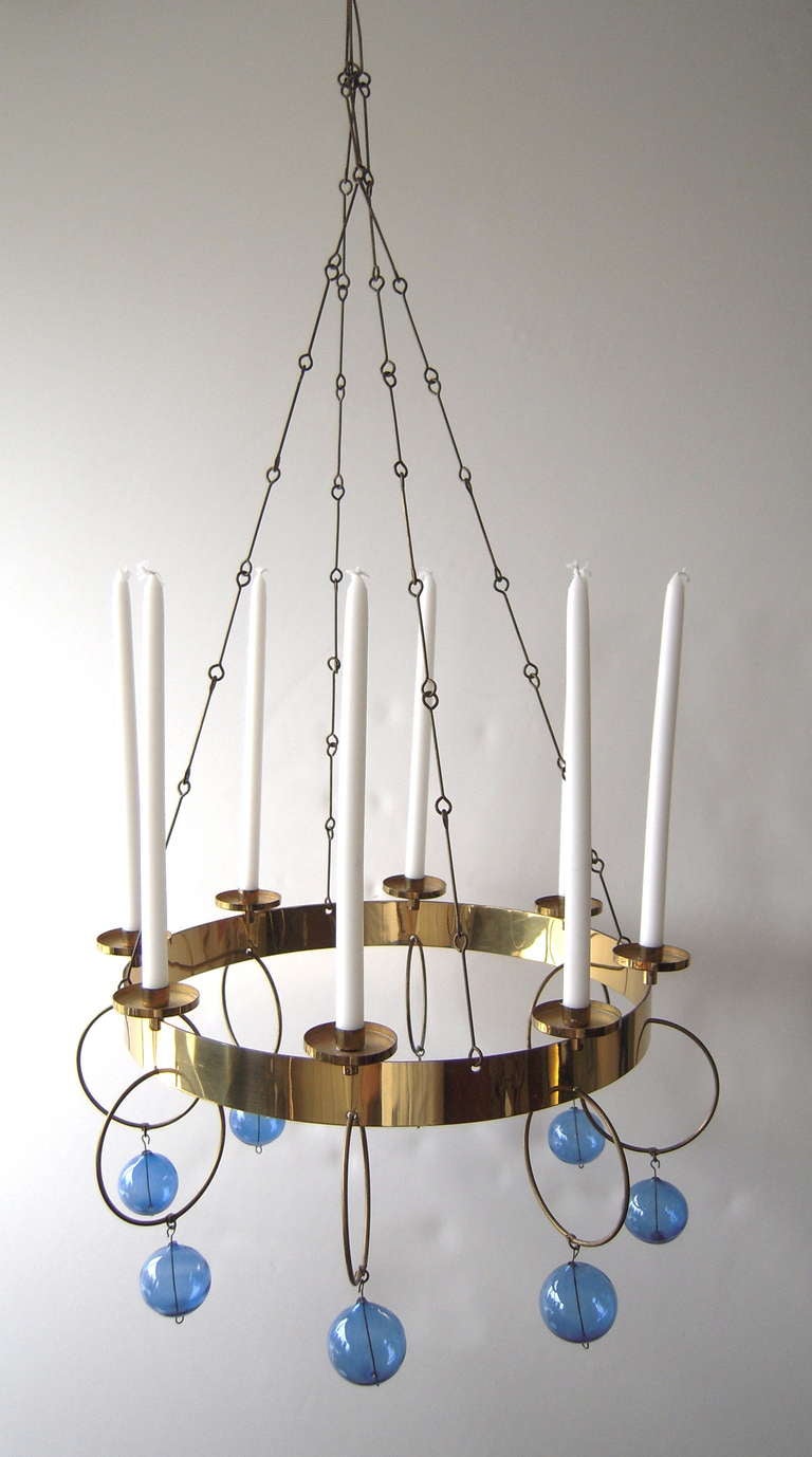 A brass and blown glass 7-light chandelier by Finnish designer Kaija Aarikka, circa 1960s, in brass with light blue hand blown glass spheres suspended from brass rings attached to a circular brass frame, suspended from a beautiful, simply geometric
