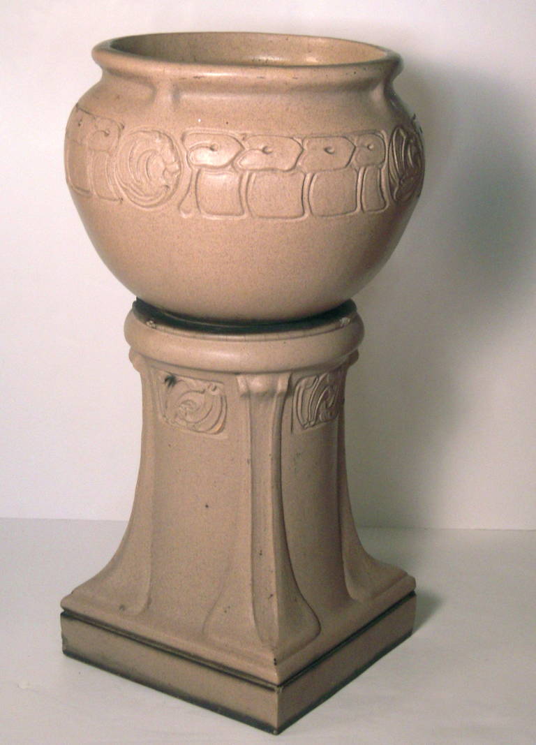 A “LEFCO”, Leeds Fireclay Co., ART NOUVEAU PERIOD GLAZED EARTHENWARE JARDINIERE ON STAND, RETAILED BY LIBERTY & CO.,  THE DESIGN POSSIBLY BY ARCHIBALD KNOX, OF GLOBULAR FORM WITH EVERTED RIM AND BAS RELIEF STYLIZED FLORAL AND FOLIATE DECORATION, ON