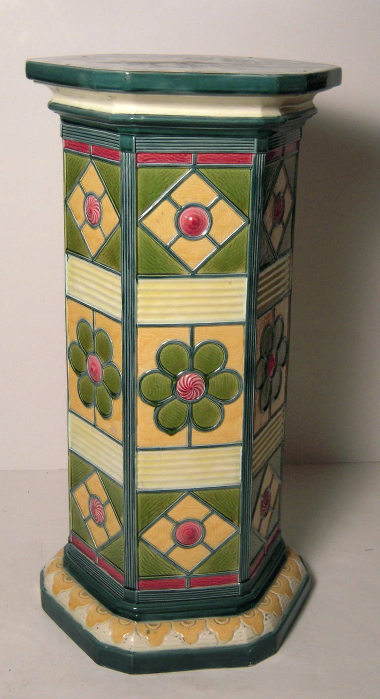 A Wedgwood majolica pedestal plant stand, circa 1880, the hexagonal too with mottled evergreen, brown and cream glazed surface over a molded hexagonal use with bands of geometric and floral designs in green, pink, cream and yellow on a conforming
