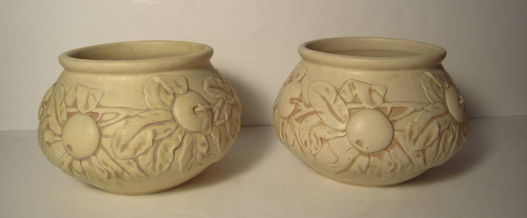 A pair of generously proportioned, bas-relief modeled Weller art pottery Baldin Apple pattern planters in buttery cream earthenware with tinted/antiqued highlights and craquelure glaze, Ohio, circa 1915-24.