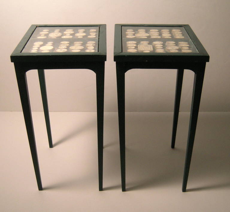 A pair of stylish and unusual green painted, glass topped rectangular occasional tables, each table housing two boxed collections of italian plaster grand tour intaglios, circa 1950s. Ideal as occasional or drinks tables.

The intaglios are