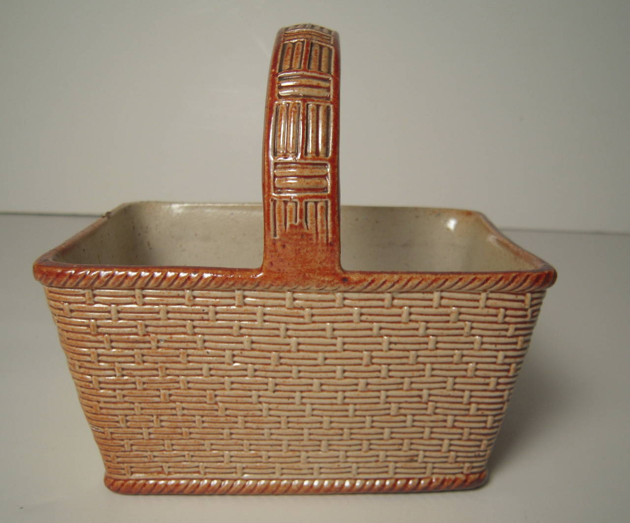 An English salt glazed stoneware pottery berry basket by S and H Briddon, circa 1848-1860, with impressed maker's mark on bottom, the basket of rectangular form with rounded corners and molded basket weave design in cream and brown glaze, with a