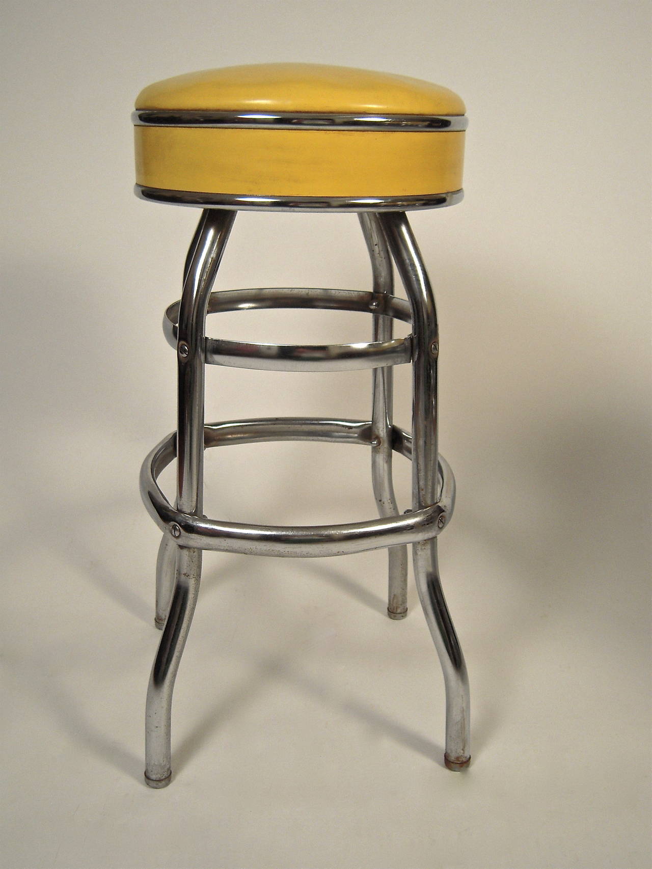A set of 4 1950s bar stools, in excellent condition, the swivel seats upholstered in original lemon yellow vinyl, on chrome plated metal legs with 2 tiers of footrests. Comfortable and fun to sit in.

Height: 31