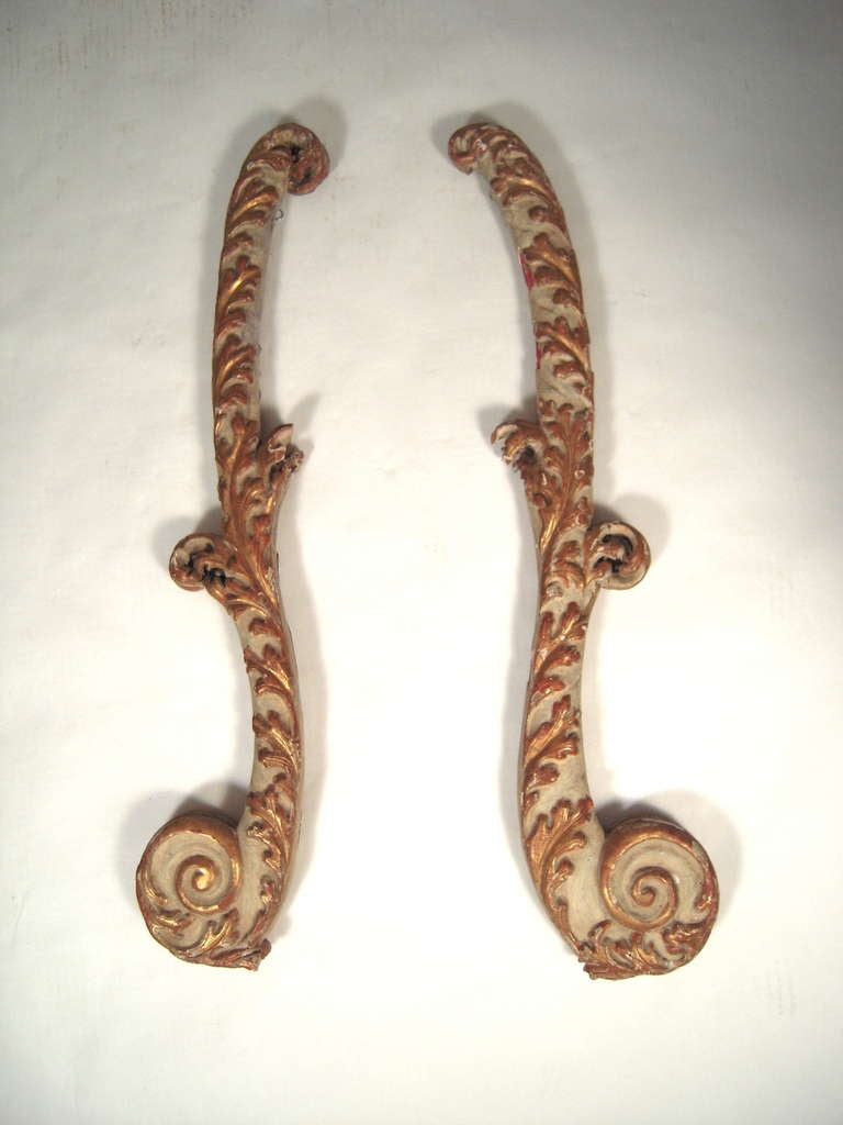 A decorative pair of 18th century Italian carved, painted and gilt wood wall decorations, originally architectural or possibly carriage (?) elements.