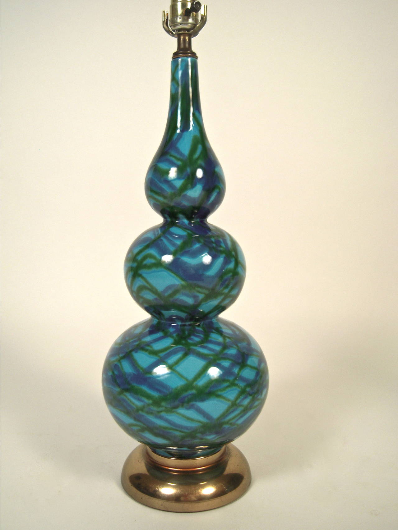 A pair of blue and green pottery lamps, circa 1960s, of triple gourd form, glazed with blue and green drip or painted decoration lines on a blue field, mounted on circular brass bases.