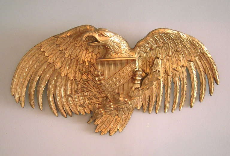 A large well carved and gilded wood American Eagle, with wings spread wide, head cocked to the right, clutching a stars and stripes shield, lightening bolts and a laurel garland in its talons.

Provenance; Stillington Hall, Gloucester,