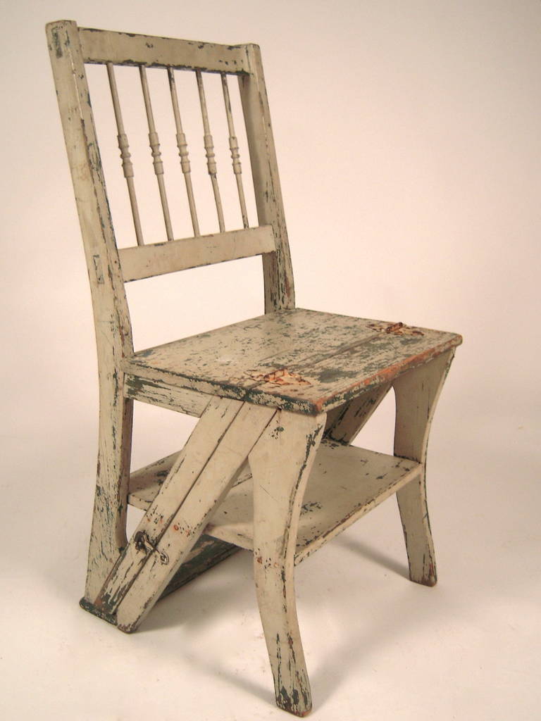 A late 19th century metamorphic chair land adder, in old white and green paint, the square back with turned spindles (1 with minor repair) over the rectangular seat which is hinged and flips over to convert the chair into a small step ladder.