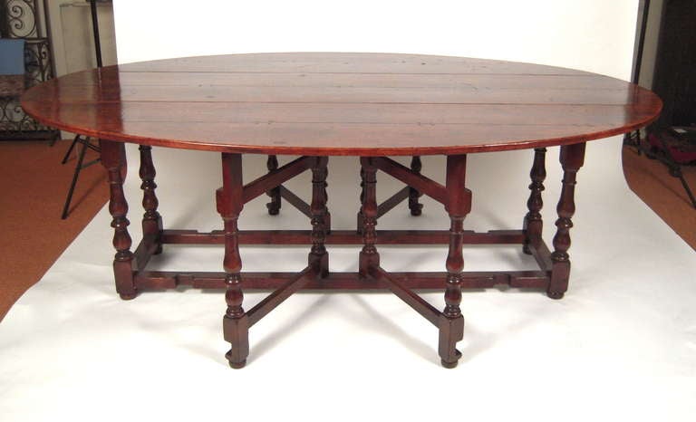 A BEAUTIFUL, LARGE OVAL WILLIAM AND MARY STYLE GATELEG DINING OR HUNT TABLE IN OAK, ENGLISH, 20TH CENTURY, THE RICHLY COLORED TOP COMPOSED OF EARLIER ELEMENTS, ON BLOCK AND BALUSTER TURNED LEGS. 

The pivoting gate legs on this table are