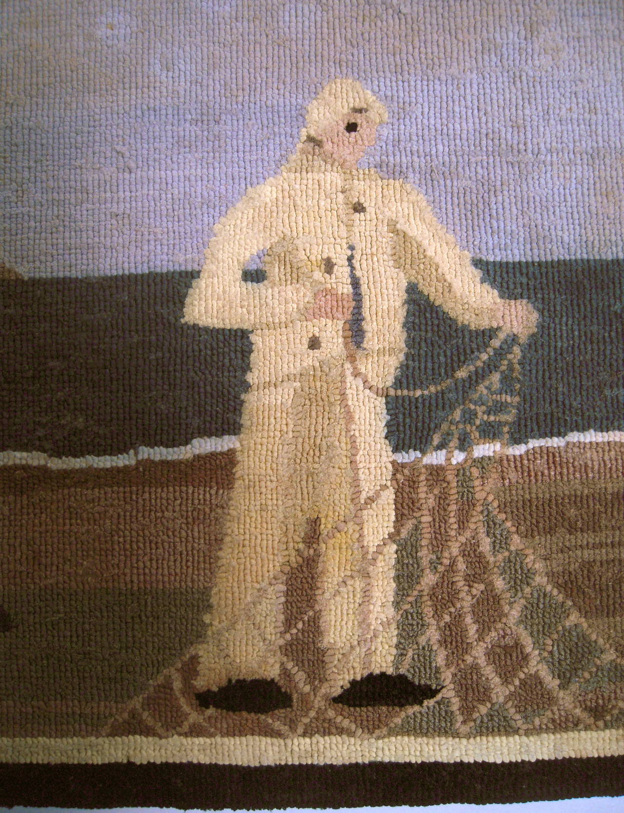 A folk art Grenfell fisherman hooked mat by the Grenfell Labrador Industries, Newfoundland and Labrador, early 20th century, composed of bleached and dyed cotton and silk strips hooked onto a burlap support, depicting a fisherman, gathering or