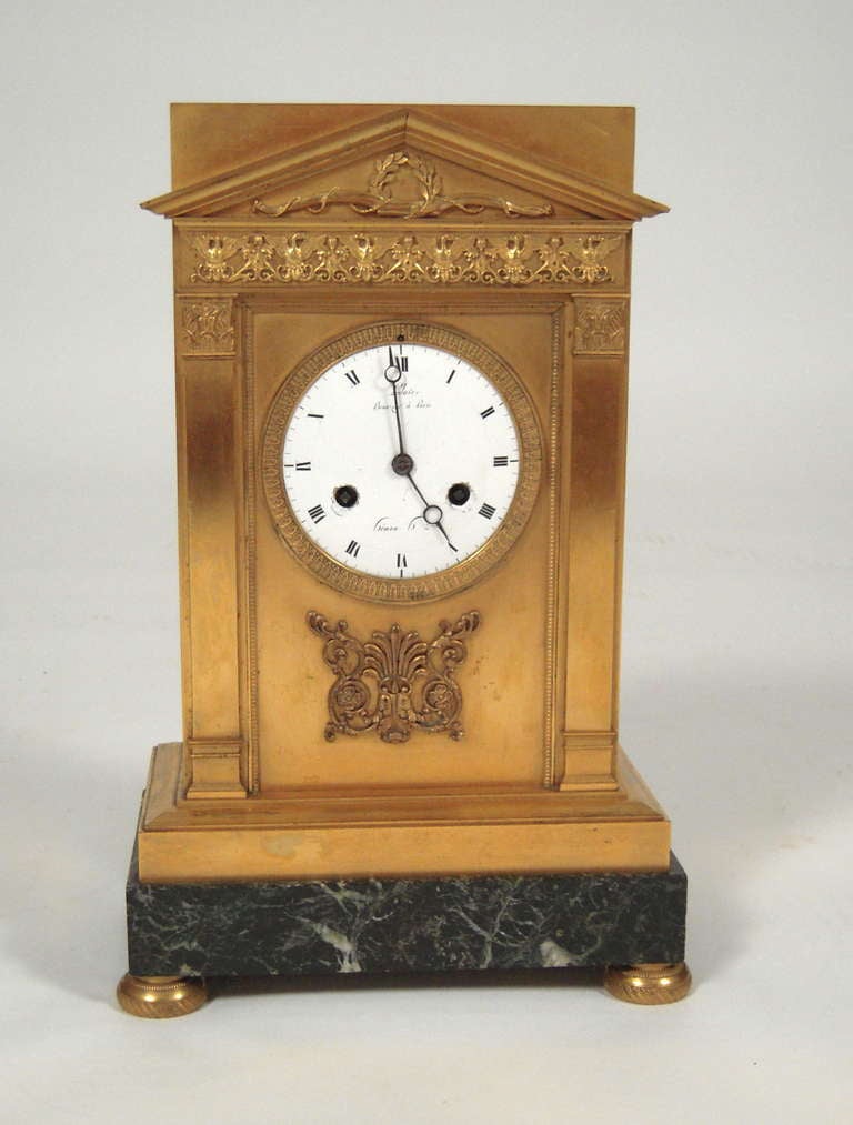 A fine quality French Empire period bronze doré mantel clock of architectural form, the triangular pediment centered with a finely modeled  tied laurel wreath over a band of Napoleonic eagles and scrollwork over two pilasters flanking a circular