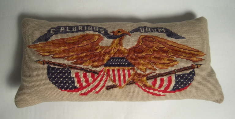 A patriotic American hand made needlepoint pillow depicting an eagle with wings spread wide, clutching an 'E Pluribus Unum