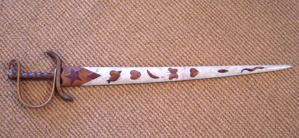An unusual carved and painted folk art swordfish bill sword, made from the bill of a swordfish, with carved wooden hilt and grip, the swordfish bill section in wood decorated with applied carved wooden star, hearts, diamond, crescent, and snake
