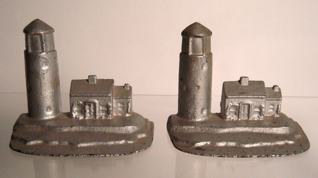 Pair of vintage cast iron lighthouse and lighthouse keeper's house doorstops in later, but old, silver radiator paint.