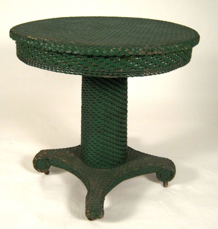 A neoclassical style round table in green painted wicker by the Heywood Wakefield Company. Wonderful contrast of classical design with country furniture materials.<br />
Great as a small dining, end or center table.