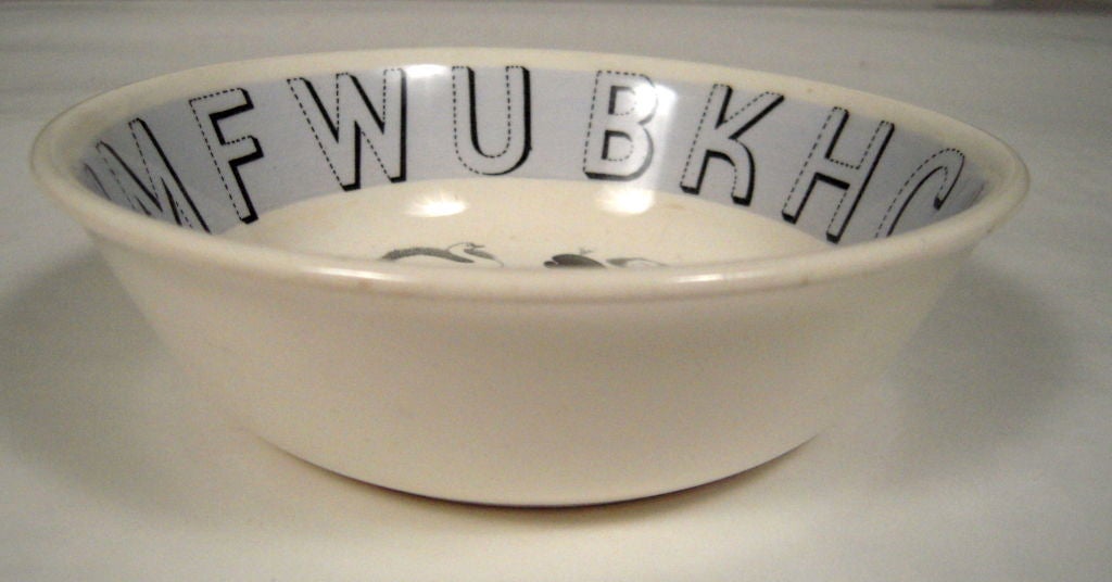 An original Eric Ravilious designed bowl for Wedgwood in the 'Alphabet' pattern, the random letters of the alphabet and a variety of stylized emblems transfer printed in black on Staffordshire white earthenware with a sky blue band. Signed with