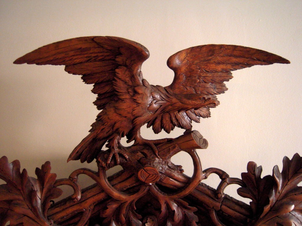 An impressive, naturalistically carved walnut Black Forest cuckoo clock, c. 1870, elaborately carved case with perched eagle at the top, the bone Roman numeral and turned wooded dial framed by carved oak leaves, acorns, and nesting bird with eggs at