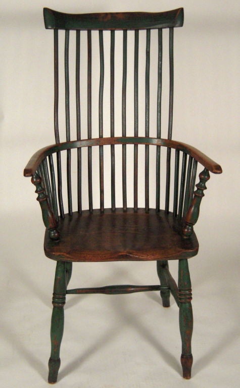 An attractive tall back windsor chair in elm, with green paint, the shaped crest over spindle back, curved arms with baluster turned supports over shaped seat raised on 4 ring-turned legs joined by a conforming H-shaped stretcher. Early 19th century