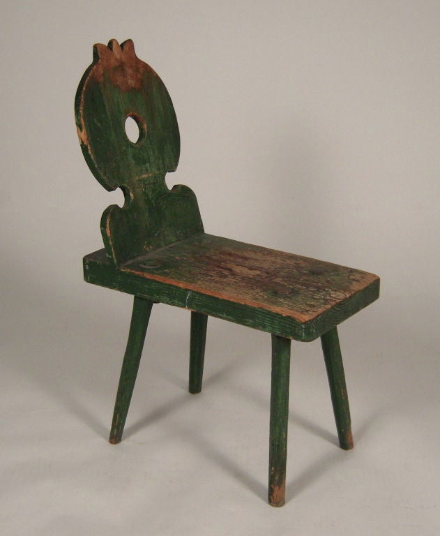 A charming 19th century green painted (cockfightng?) chair  with a circular  carved, cut out back reminiscent of European alpine chair design, with elongated rectangular seat which makes this chair also very practical as a side table.  Good color,