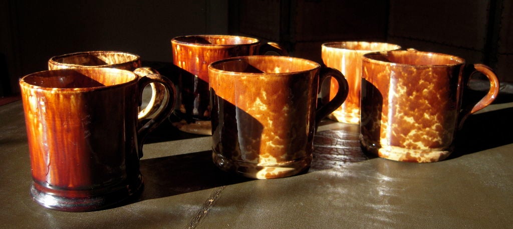 A collection of 6 19th century Rockingham brown glazed ceramic mugs, each of cylindrical form with applied strap handles, all similar in size, with variations in shape and glaze.