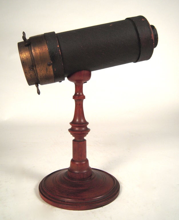 A 19th century American parlor kaleiodoscope in superb condition, the black painted pasteboard, cylindrical viewing tube terminating in a brass 'ship's wheel' which when turned reveals an ever changing array of colorful geometric designs formed by