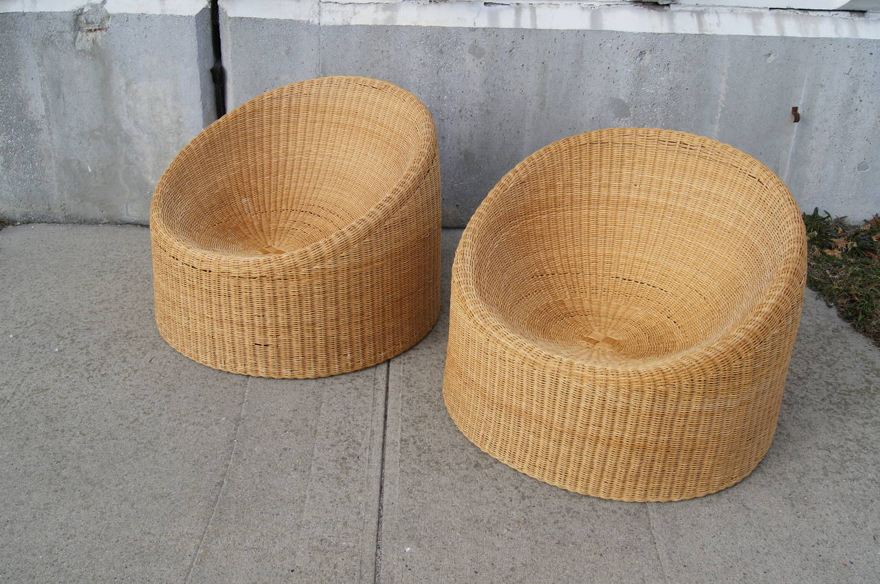 This pair of chairs were designed in Finland by famed designer Eero Aarnio. These chairs feature a unique round design and are composed of woven wicker.