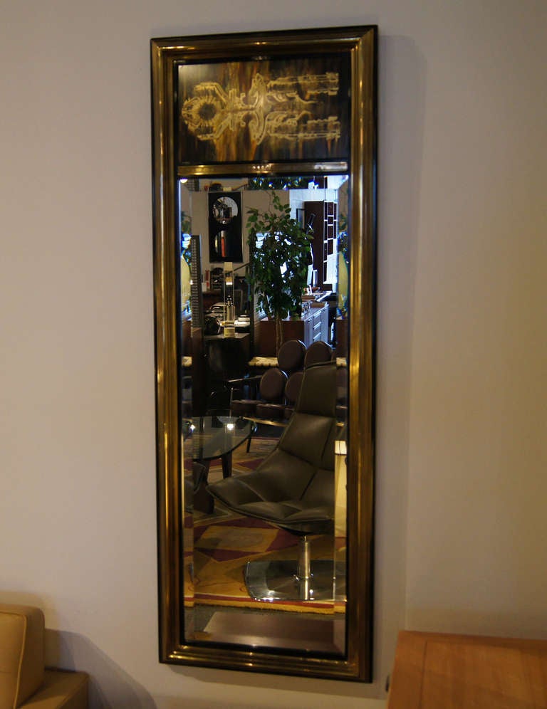 Bernhard Rohne designed this beautiful mirror for Mastercraft in the 1970s. A frame of black lacquered wood with applied brass surrounds the long bevelled mirror; the panel above features one of Rohne's signature acid-etched brass designs.