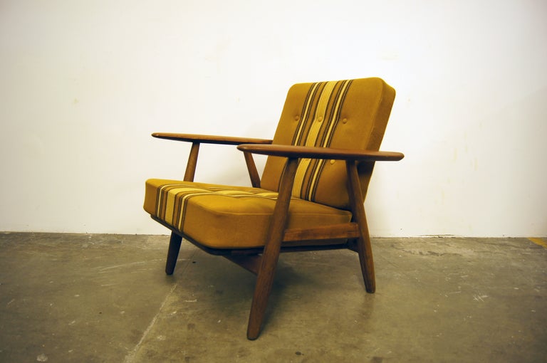 This armchair by Hans Wegner for Getama, known as the cigar chair, features a solid oak frame with original spring cushions and upholstery. 