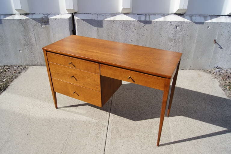 This writing desk was designed by Paul McCobb for Winchendon Furniture's popular Planner Group line. It is constructed of solid maple and features four drawers with brass drawer pulls. Original label intact.