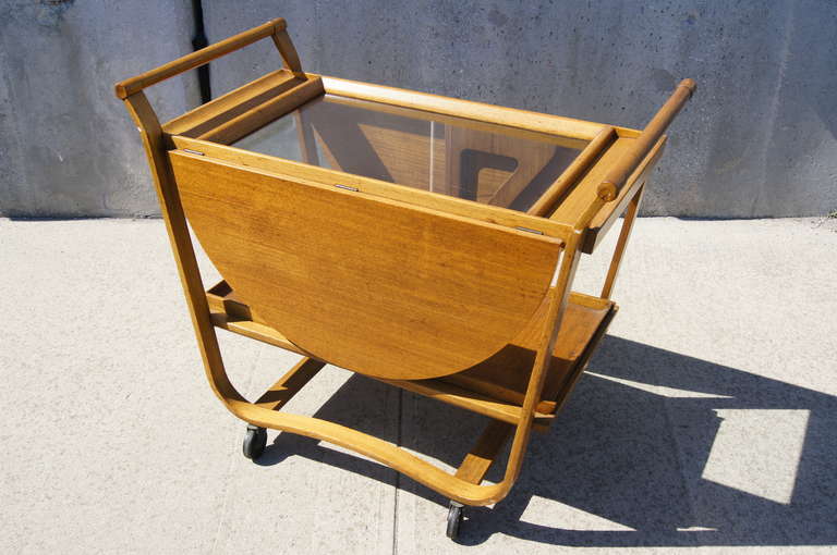 This beautiful tea cart has a sculptural elegance. With both leaves extended this piece measures 49″ wide. Featuring two removable trays and a unique inlaid glass top, this tea cart is as attractive as it is functional.