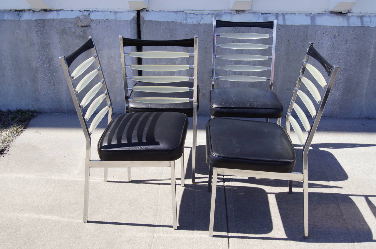 These striking dining chairs feature chrome frames, vinyl seats, and lucite and plastic backs.