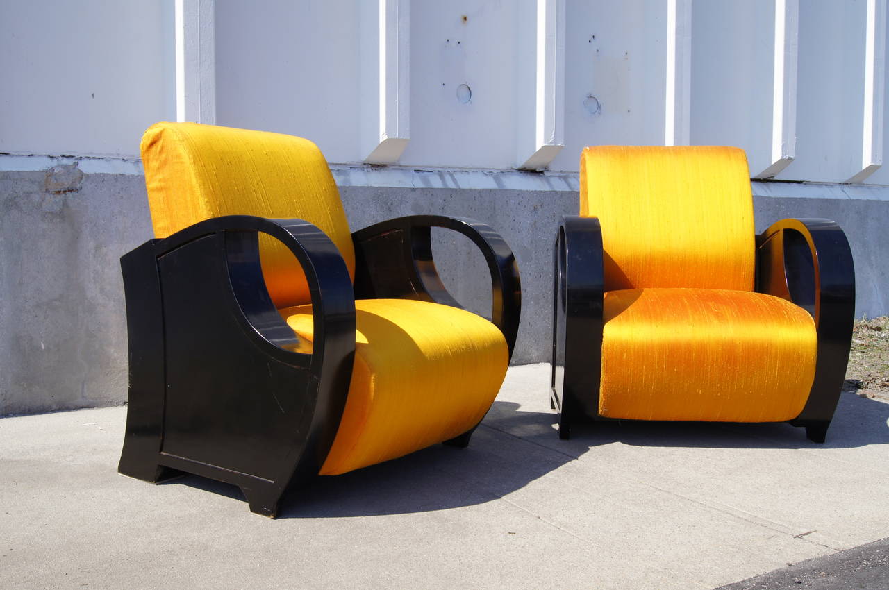 This exuberant pair of European art deco club chairs frame generous, comfortable seats between muscular curves of ebonized wood. 

They are very solid and in excellent structural condition, but should be reupholstered and would benefit from having