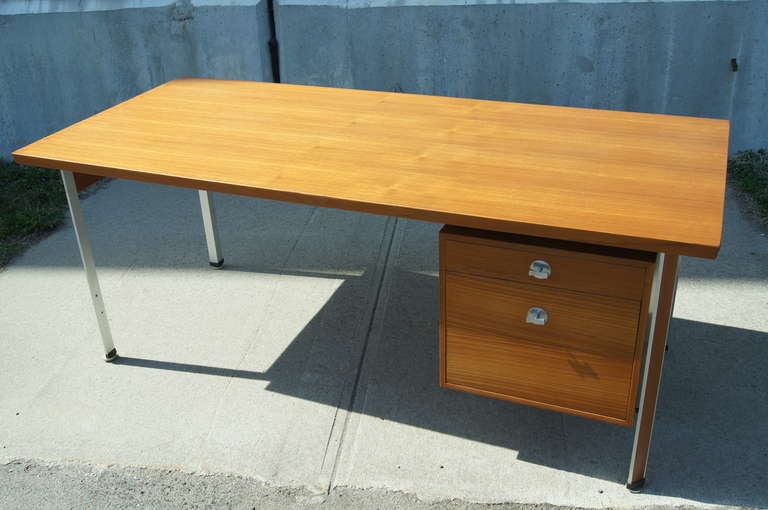 This handsome teak desk, designed by Finn Juhl in the 1960s, stands on canted teak and aluminum legs. The suspended case features a shallow drawer and a filing cabinet, each with striking aluminum bow-tie pulls.