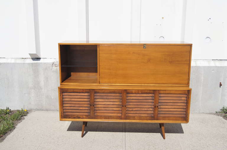 This unique cabinet was designed by Paul McCobb for Winchendon Furniture's popular Planner Group line. It is composed of two separate components: an upper secretary section and a lower section with enclosed shelving. The secretary door opens for