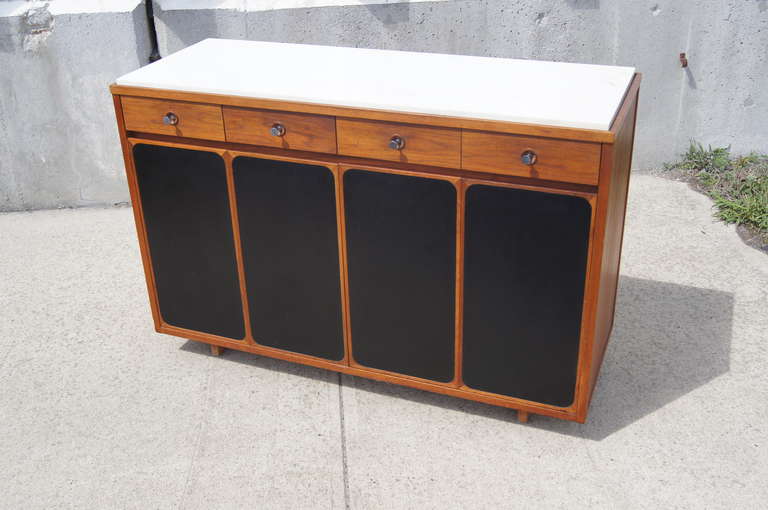 This buffet was designed by Paul McCobb for H. Sacks & Sons. It is constructed of walnut and features an inset marble top. This piece provides ample storage with four upper drawers and eight lower drawers that are concealed by leather-front