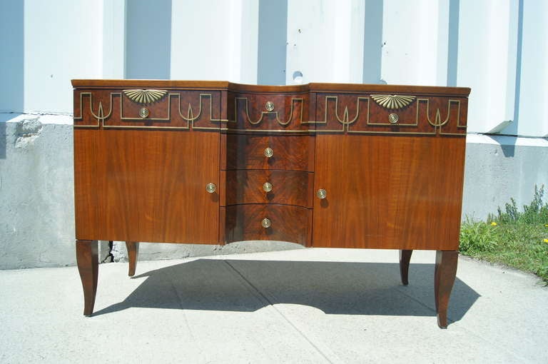 This elegant sideboard by John Widdicomb, modeled after Gio Ponti’s 1931 sideboard for R. B. da Turri, is composed of beautiful walnut veneer and walnut burl with decorative brass accents and knobs. It features four concave drawers between two