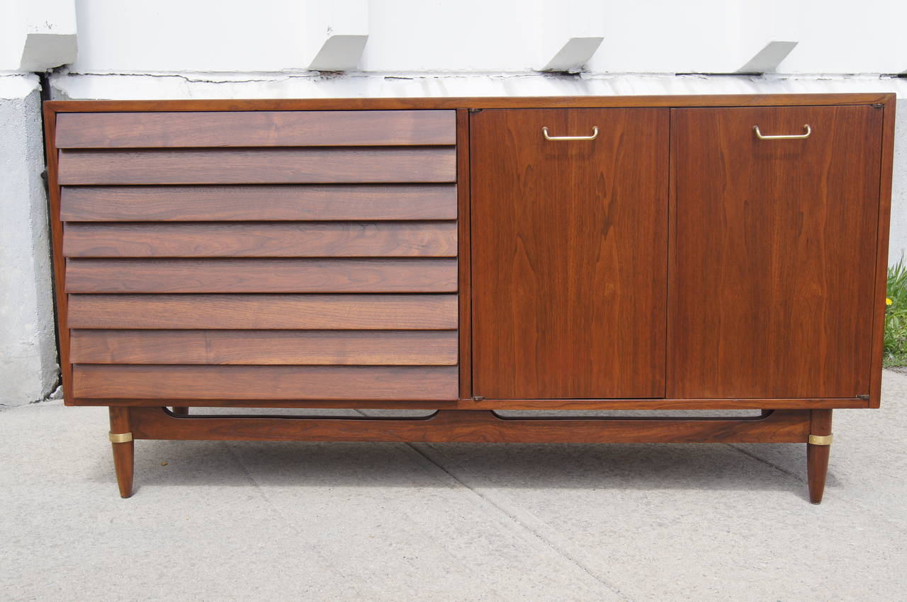 Merton Gershun designed this handsome walnut sideboard for Martinsville’s Dania collection. On the left, three deep louvered-front drawers create a seamless flow. On the right, two doors with brass pulls conceal three white lacquered drawers and
