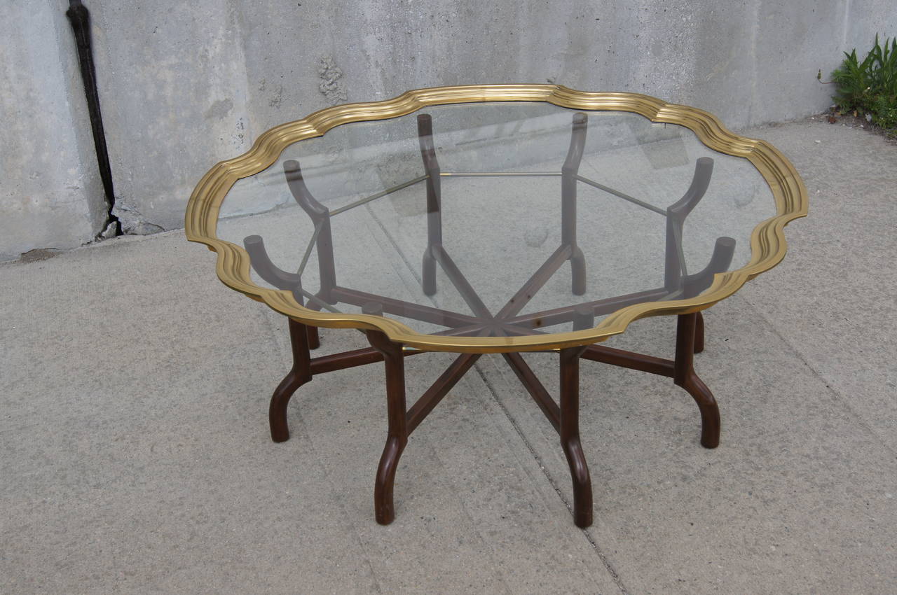 A well-crafted Hollywood Regency offering, attributed to Baker Furniture, this coffee table comprises a radiating eight-leg wood and brass base and a scalloped tray top of glass rimmed in solid brass.


 