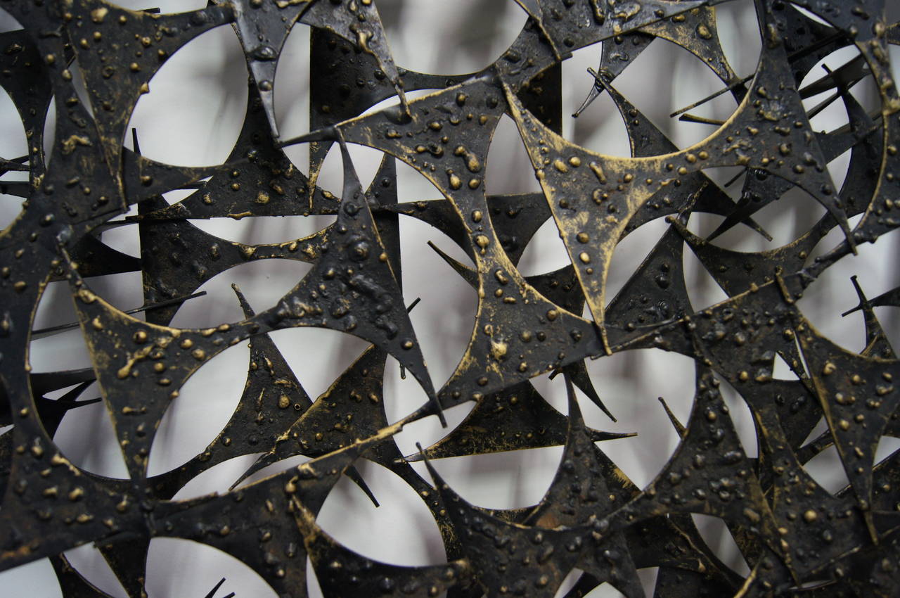 Designed by Marc Weinstein and inspired by his time working in a scrap metal yard, this energetic starburst wall sculpture is composed of many pieces of brass with a dark patina.