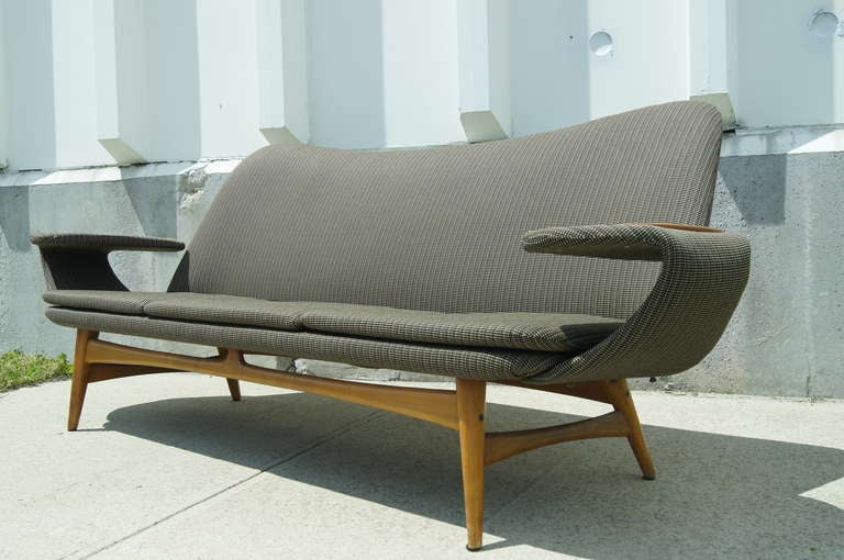 This sofa is a unique example of modern Scandinavian furniture design with its expressive form and distinguished details. Designed in Norway but Rastad & Relling in 1956. The curved arms provide a surface area for resting drinks, making them both
