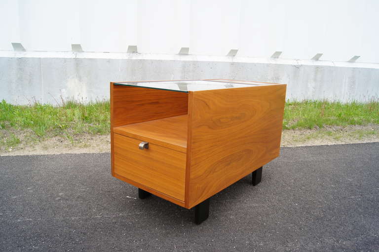 George Nelson designed this uniquely functional side table, model 4745, for Herman Miller. Constructed of walnut with ebonized block legs, it houses two square copper planting boxes with wooden covers for flexible arrangements; a glass top over a